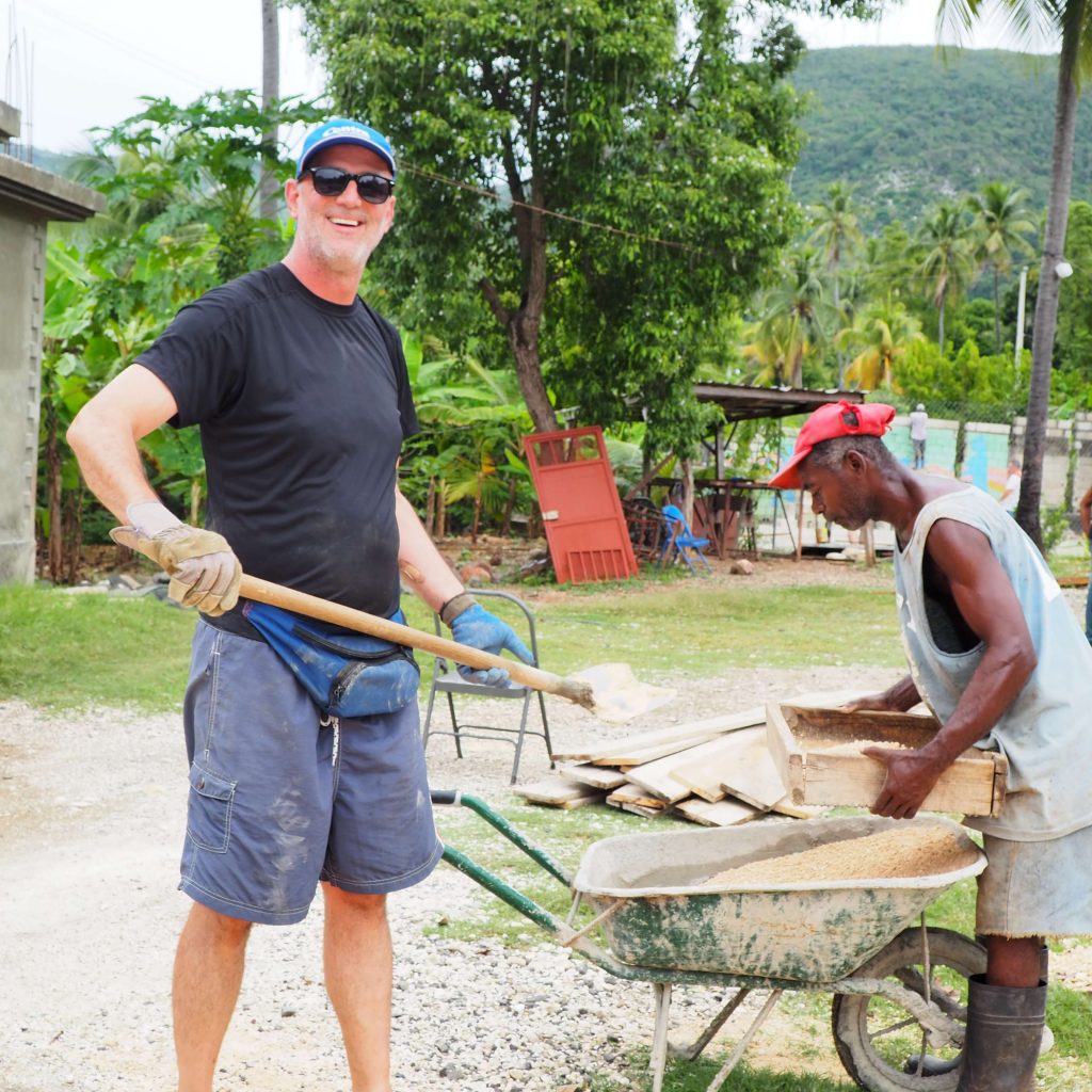 Andrew Creighton working with the locals loading a wheelbarrow.